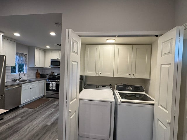 Inside washer and dryer with storage cabinets behind folding doors next to entryway
