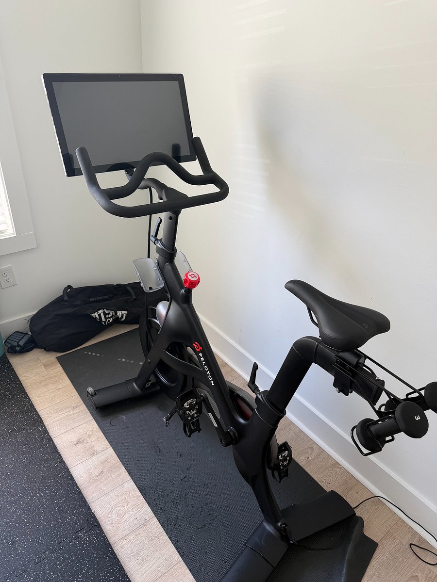 Gym featuring Peleton, adjustable dumbbells, and weight bench.