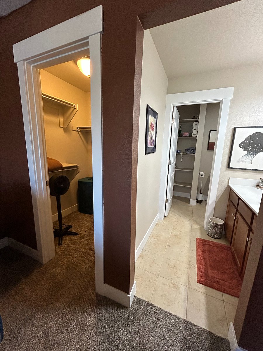 walk in closet with hangers, extra linens (regular and flannel), laundry hamper, and extra fan.
