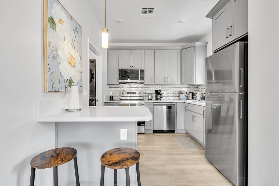 Fully equipped kitchen with stainless steel appliances, quartz countertops, and convenient breakfast bar seating for casual meals or morning coffee.