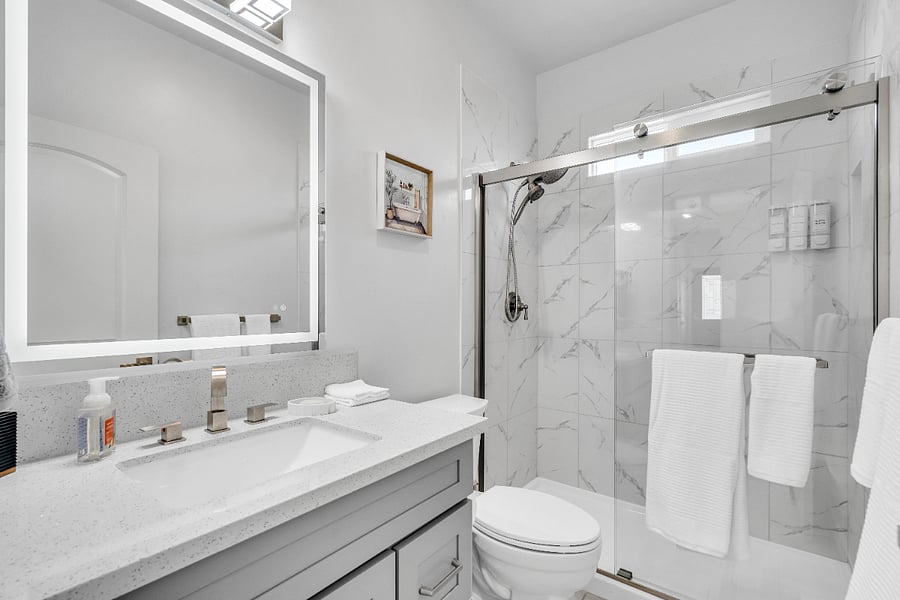 Clean and modern full bathroom featuring a walk-in glass shower, fresh towels, and complimentary essentials.