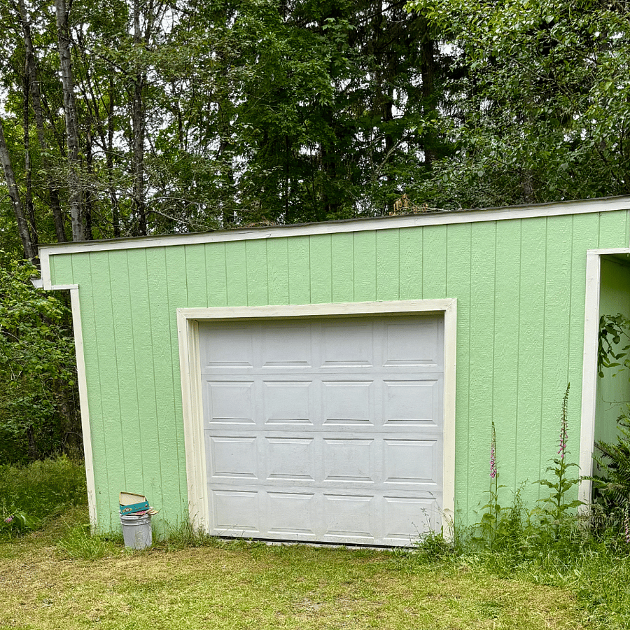 Single car garage contains a rack of garden tools and a hand-truck dolly