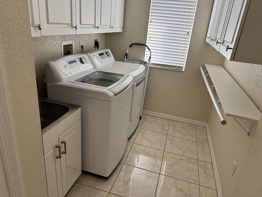 Laundry room has a sink, iron, ironing board, cleaning supplies storage and high-capatiy washer and dryer.