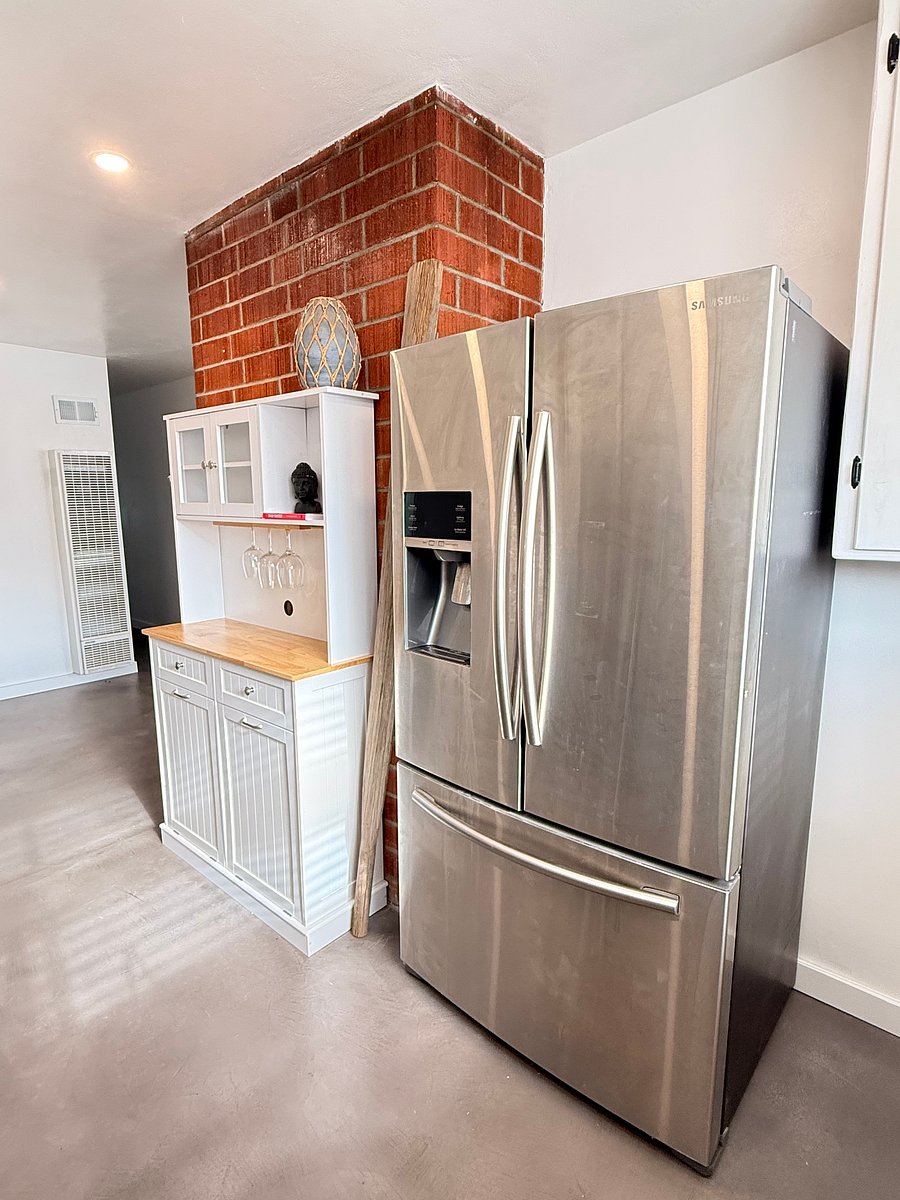Fridge, free standing trash with recycling bins, and cabinet top.