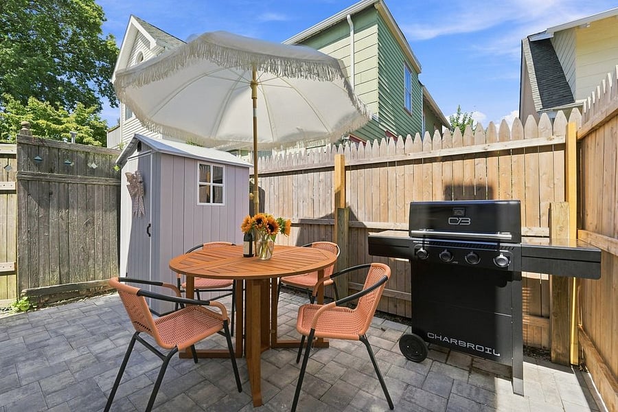 Small courtyard style backyard equipped with shed for beach things, table for 4 with umbrella, and brand new BBQ perfect for days or evenings at home