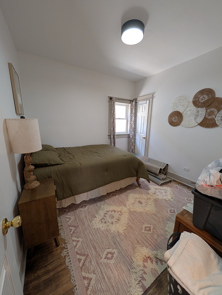 Bedroom with full bed, mid-century nightstands, TV, and rattan wall decor.