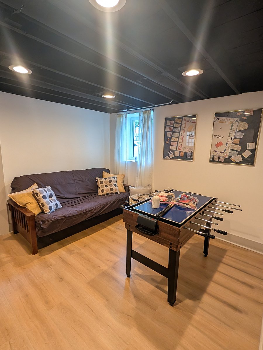 Rec space with multi-game table, futon, and framed Monopoly wall art.