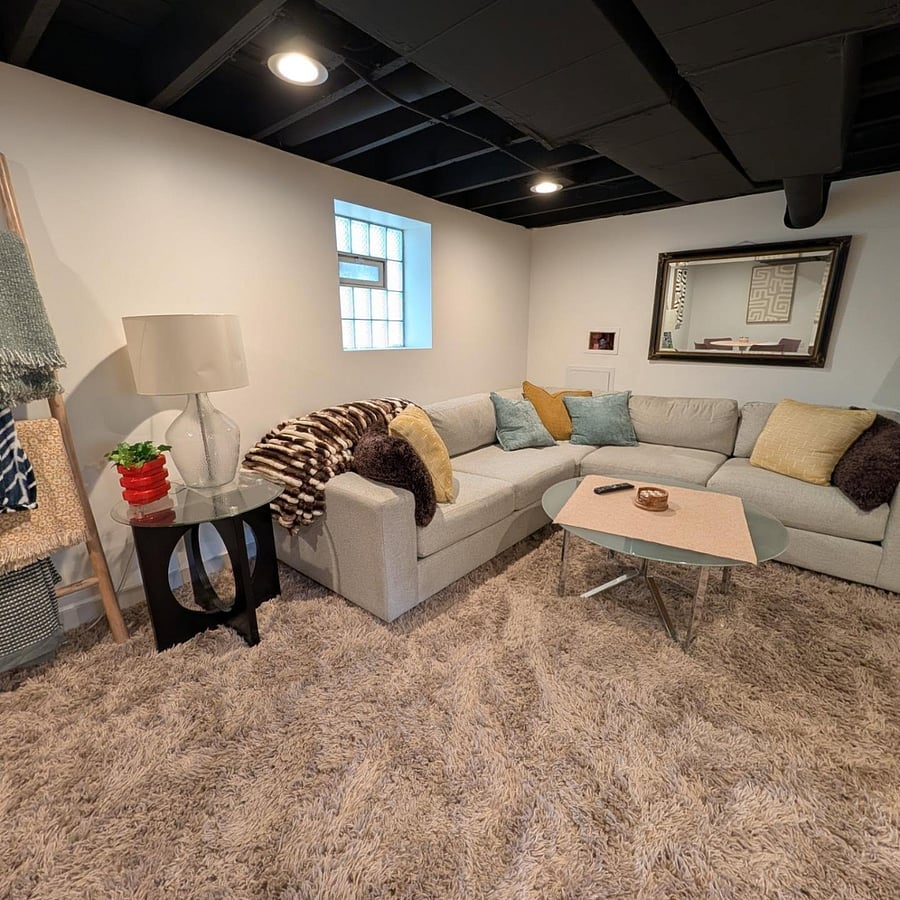 Lounge area with oversized sectional, throw blankets, mirror, and recessed lighting.
