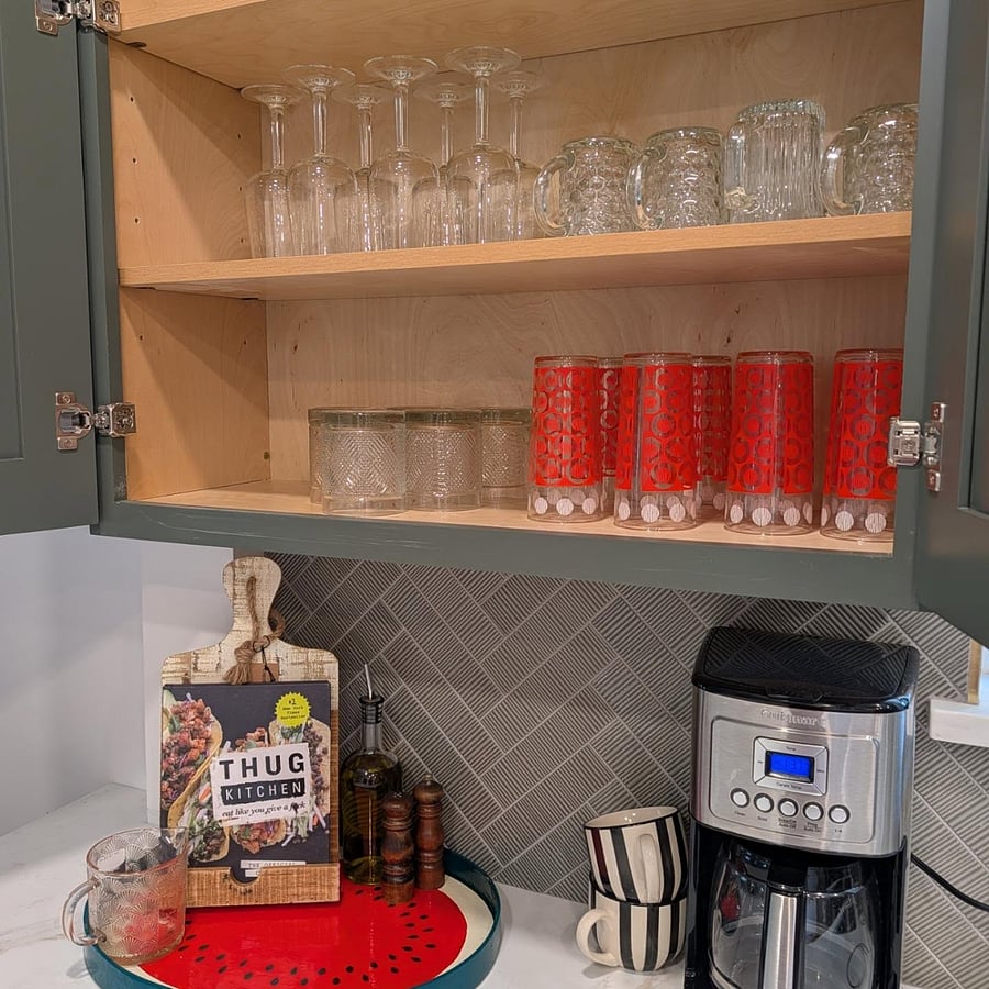 Stocked kitchen cabinets with wine glasses, mugs, and tumblers, plus a programmable Cuisinart coffee maker.