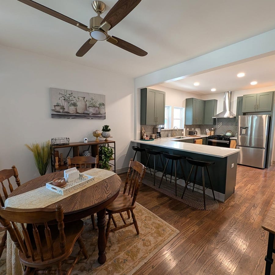 Main living floor with dining table for four, hardwood floors, and breakfast bar seating for four at the open kitchen.