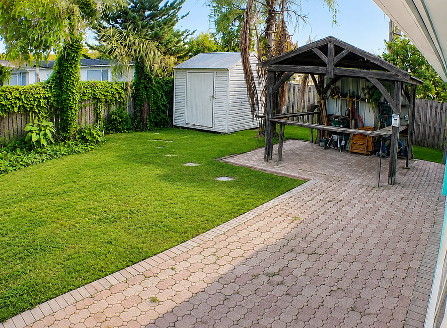 Private backyard with a patio, grassy area, tropical landscaping, and covered outdoor bar area.