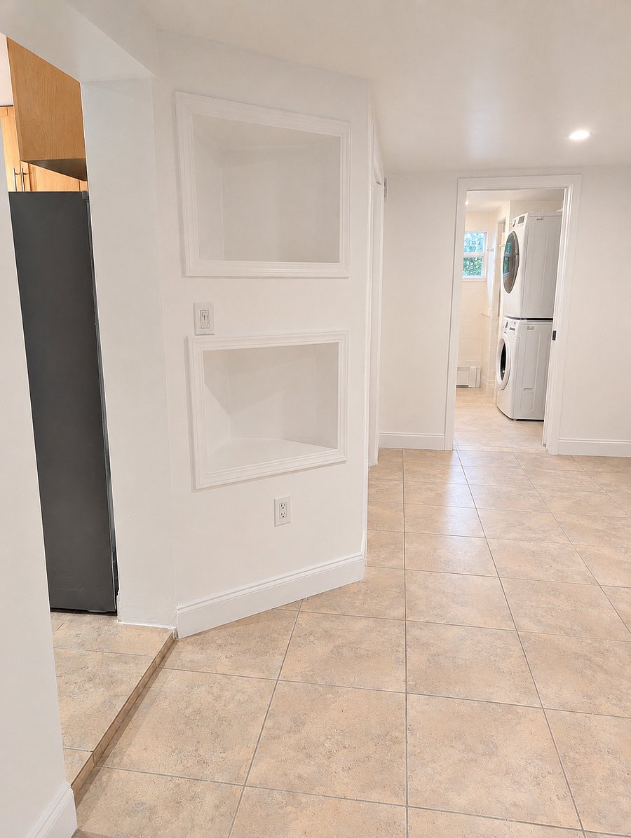 Second view of the bonus room, showing storage shelves, clothes hanging space, and access to the bathroom/laundry room.