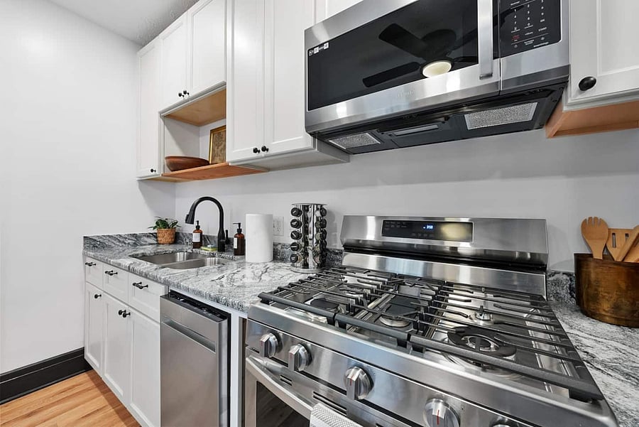Gas oven and range with cooking utensils and pots and pans provided.
