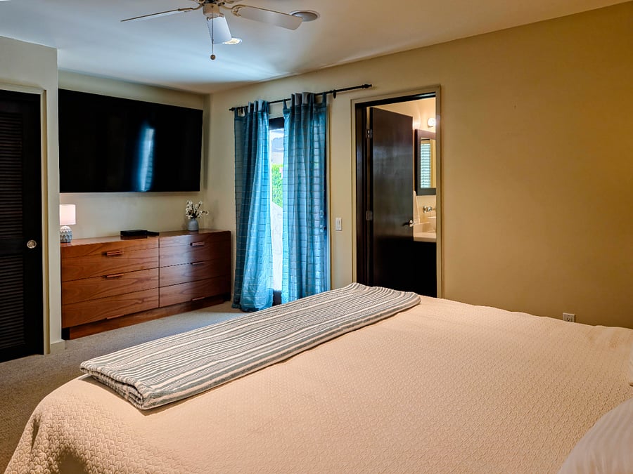 Primary bedroom. Door with curtain leads to the back patio. Ample dresser and wall closet space.