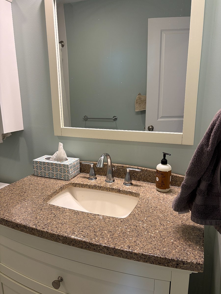 Clean shared full bathroom with vanity storage.