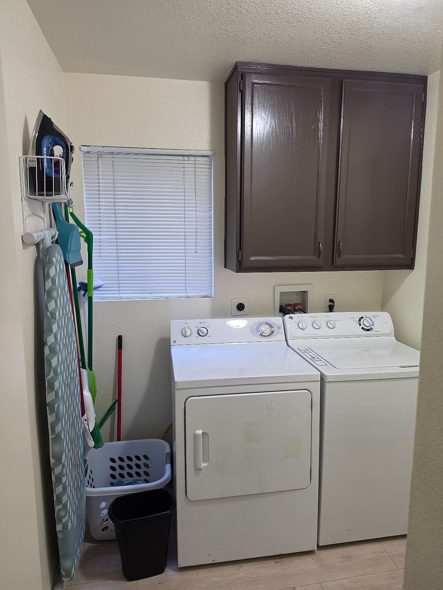Laundry room with cleaning supplies, ironing board, iron, broom and mop.