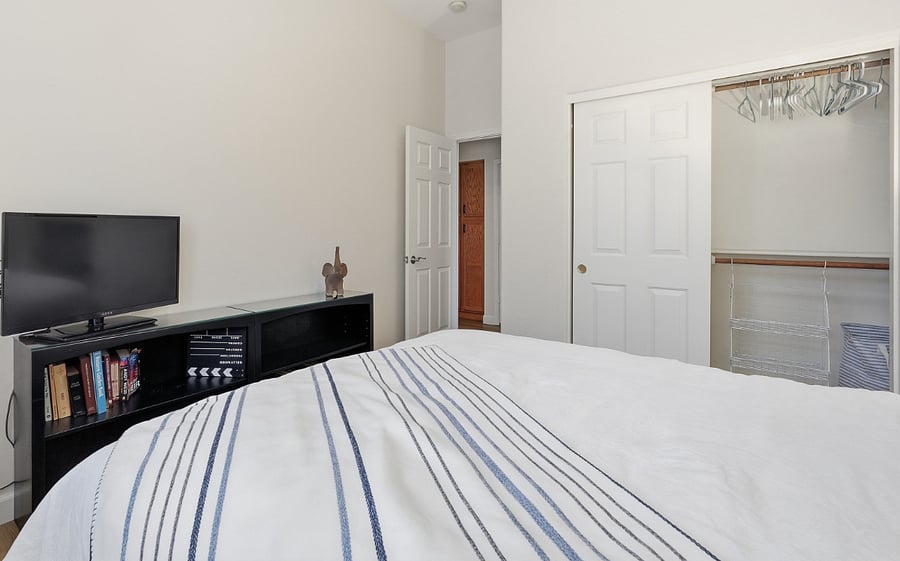 Queen bedroom 1 with Smart TV, bookcase, hanging shelves for storage in the closet.