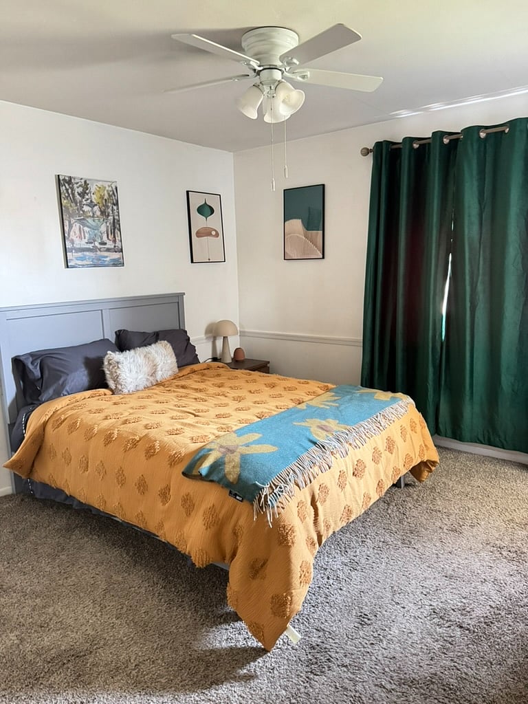 Queen bedroom with a lit-up closet, full dresser, blackout curtains, and en-suite bathroom.