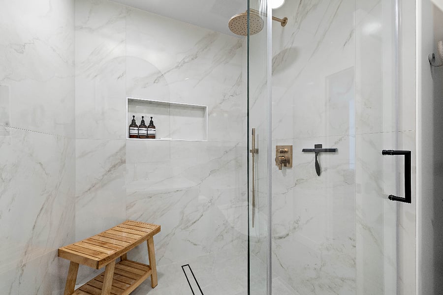 Walk-in rainfall shower with detachable shower head, shower bench, toiletries, and a spa-inspired design.
