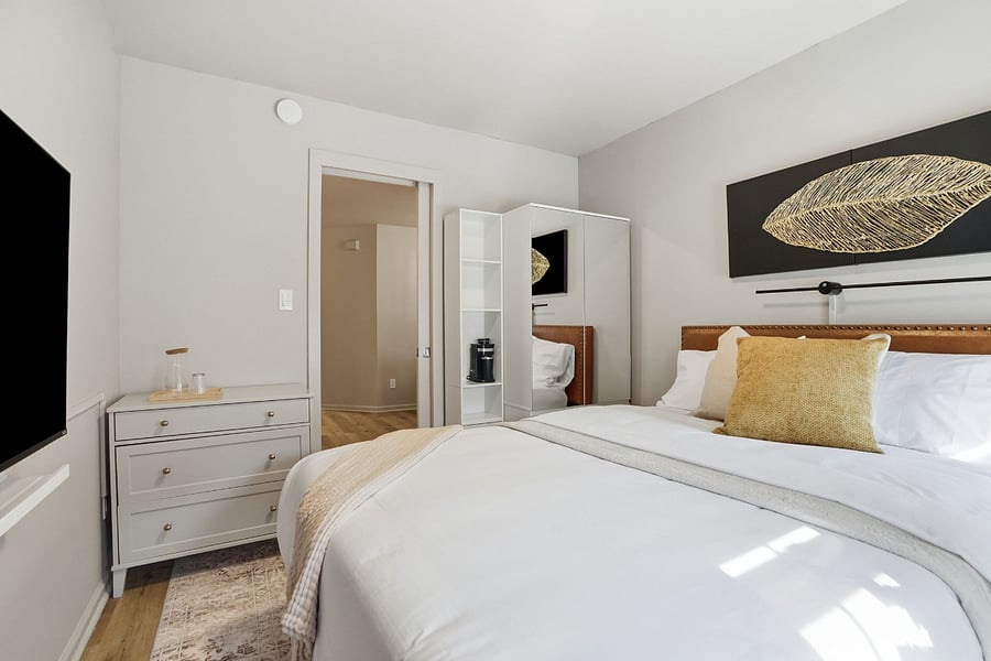 njoy a thoughtfully furnished private retreat with a queen bed, Smart TV, personal coffee station, dresser, and convenient in-room storage.
