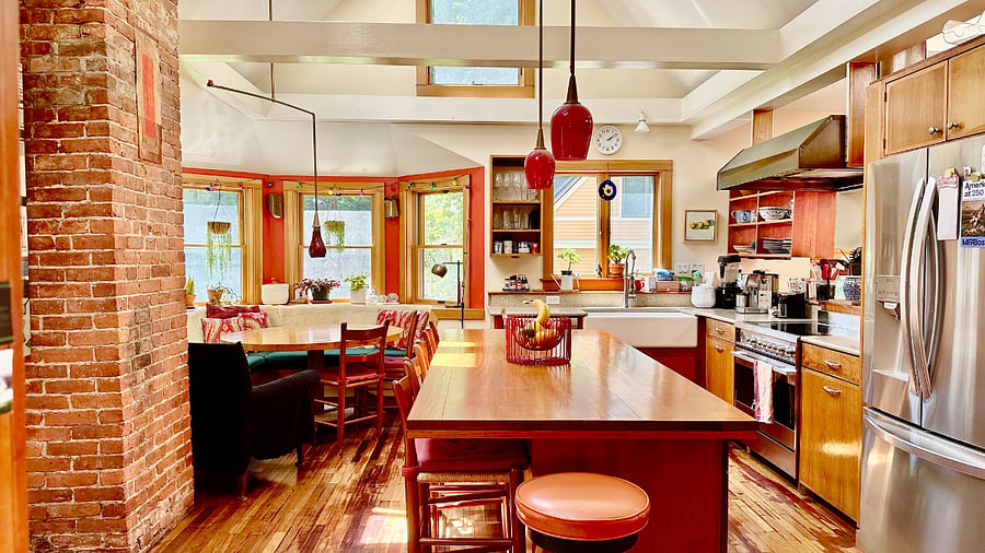Gourmet kitchen with island, dining table, benches, double height ceiling, with many appliances and lots of equipment