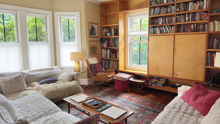 Living room with multiple couches and large screen TV behind wooden panels