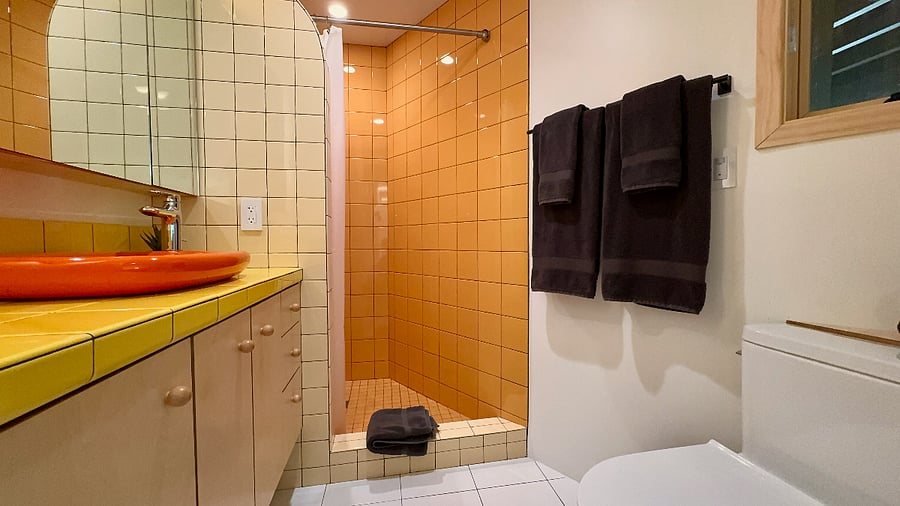 The bathroom features a spacious shower enclosure and colorful custom tile throughout.