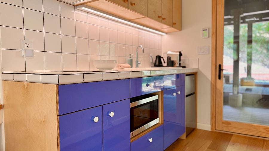 Kitchen area features Nespresso machine, two-burner induction cooktop with vent hood, microwave oven with convention and air fryer features, mini-fridge with dedicated freezer. *Note: There is no full-sized oven in space.