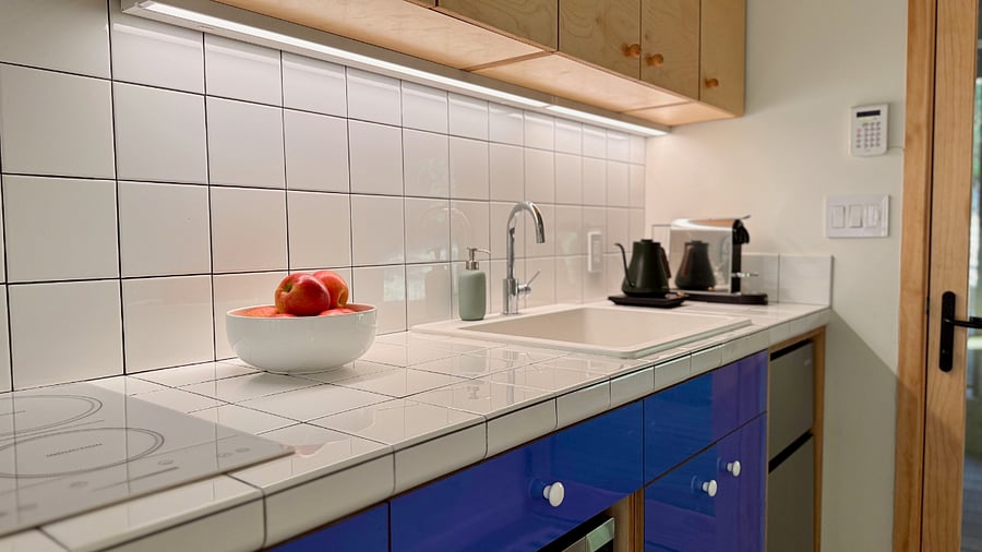 Kitchen area features Nespresso machine, two-burner induction cooktop with vent hood, microwave oven with convention and air fryer features, mini-fridge with dedicated freezer. *Note: There is no full-sized oven in space.