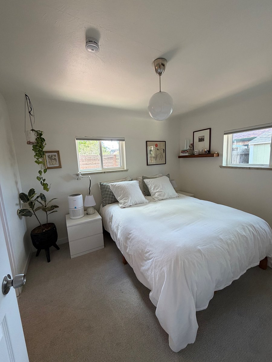 Primary Bedroom: Bright and comfortable room with a queen bed and a large freestanding closet system with ample storage for two people.