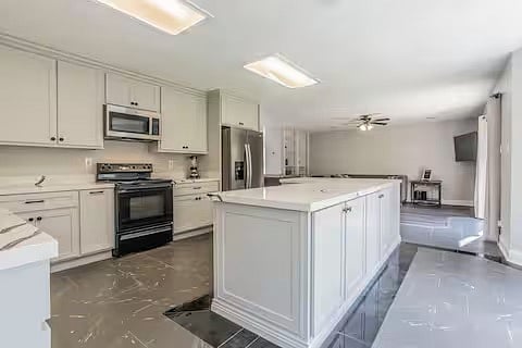 Kitchen island with cabinets on 3 sides. New refrigerator, stove and new microwave.