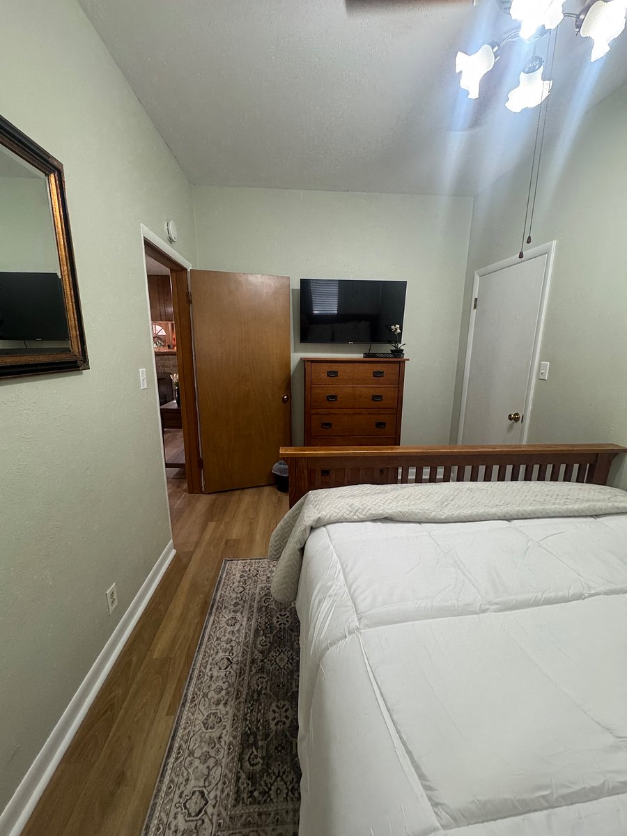 Guest bedroom features a queen bed, smart TV with dresser and closet.