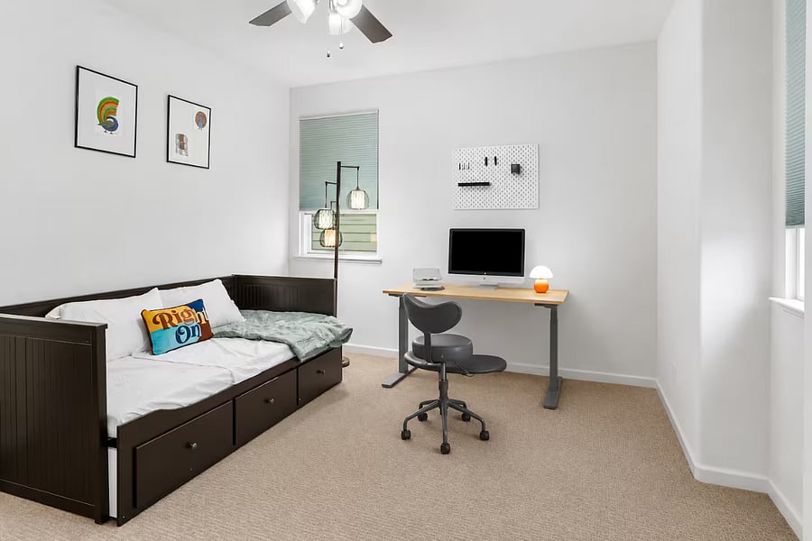 Bedroom #4  Features a twin bed, a dedicated height adjustable workspace with an ergonomic chair, and an ensuite walk-in closet, offering a comfortable setup for both rest and productivity.