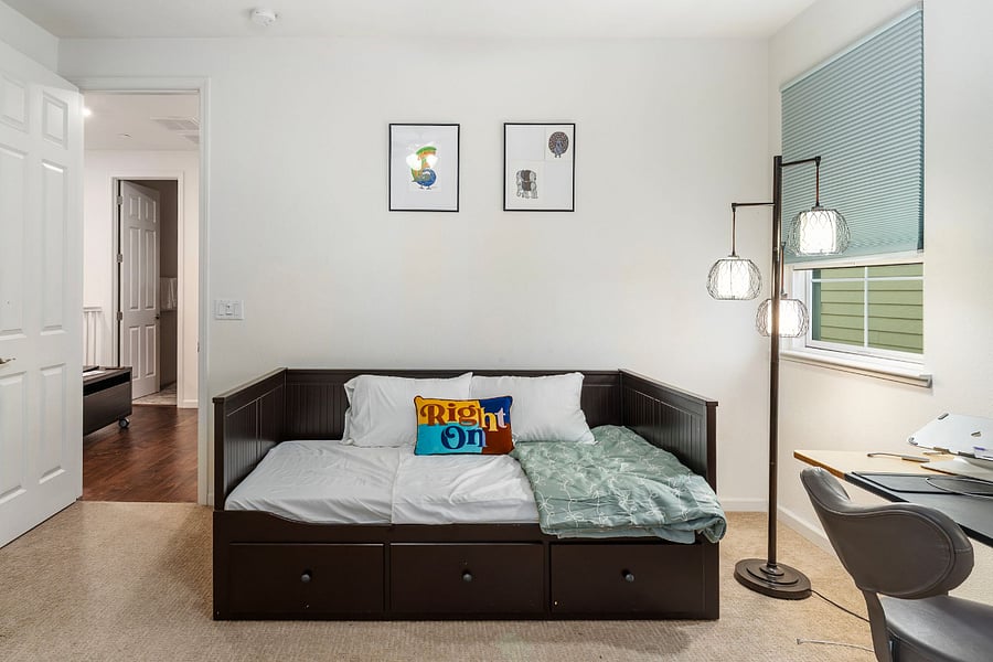 Bedroom #4  Features a twin bed, a dedicated height adjustable workspace with an ergonomic chair, and an ensuite walk-in closet, offering a comfortable setup for both rest and productivity.