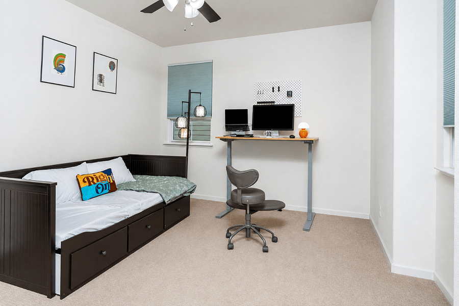 Bedroom #4 Features a twin bed, a dedicated height adjustable workspace with an ergonomic chair, and an ensuite walk-in closet, offering a comfortable setup for both rest and productivity.