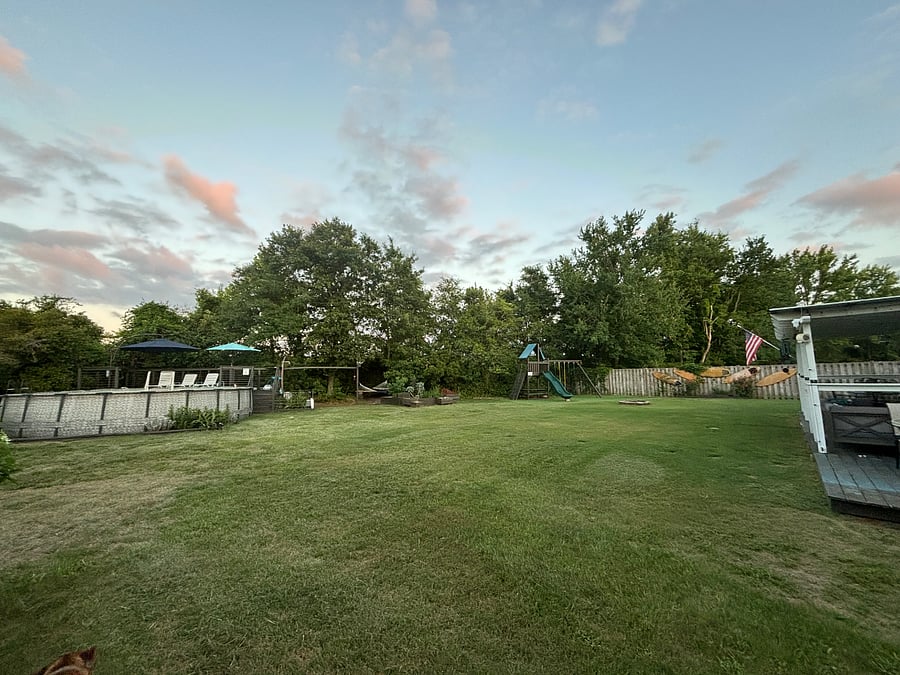 Large fenced in back yard with covered patio, swing set, multiple outdoor dining areas and grill