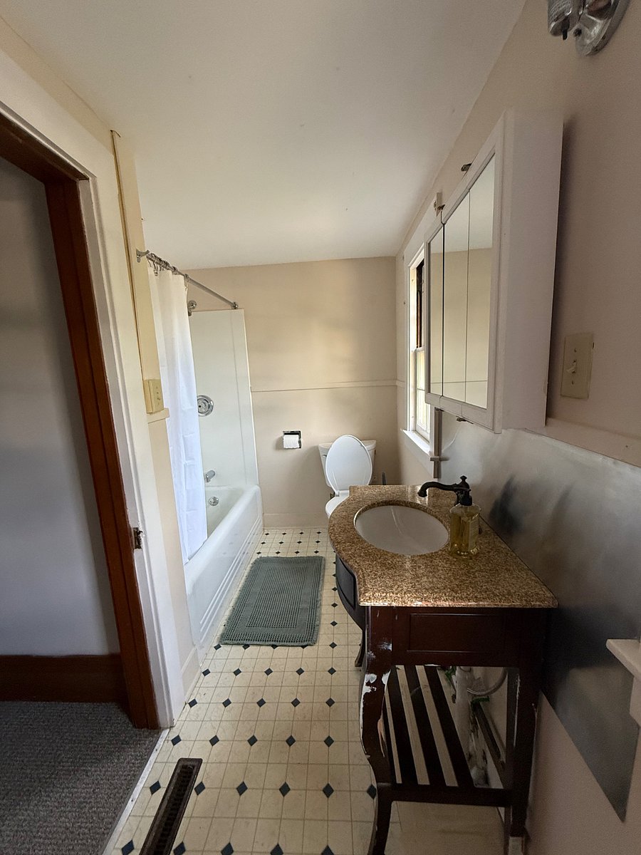 Upstairs bathroom with porcelain tub/shower and granite counter top.