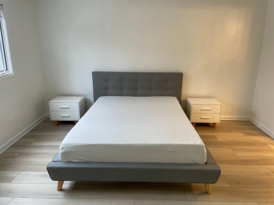Primary bedroom with queen bed, mattress, two nightstands, and floor lamp.