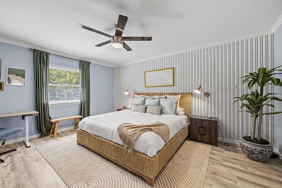Luxurious primary bedroom with a king bed, height-adjustable workspace, smart TV, and walk-in closet.  A refined retreat offering comfort, style, and elevated relaxation.