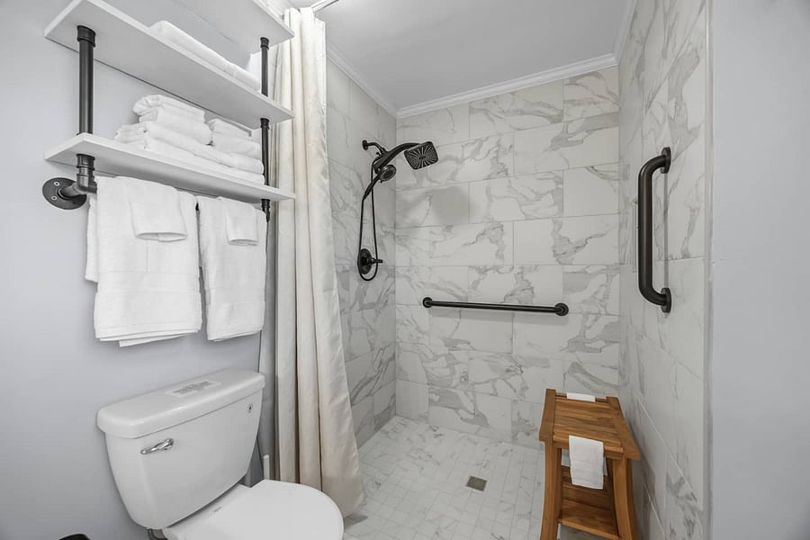 The primary bathroom features a zero-entry shower with secure built-in handrails for easy access.  The shower is fully stocked with shampoo, conditioner, and body wash.  A shower chair with arms and back is also available upon request.