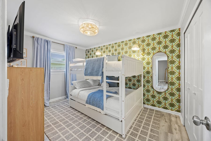 This bright bunk room features full-size bunk beds plus a twin trundle, providing flexible sleeping arrangements ideal for families, kids, and group stays.