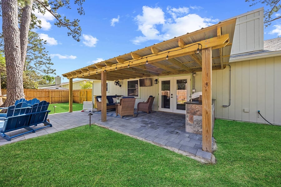 Relax on the covered patio, complete with shaded seating and easy access throughout the backyard.  Raised pavers create a smooth, wheelchair-friendly path connecting the grill, gathering spaces, and a cozy fire pit area.