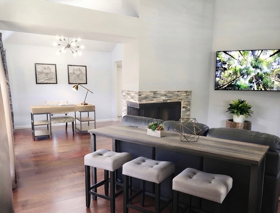 Living room features 2 seating areas and console area. Large TV and beautiful windows.