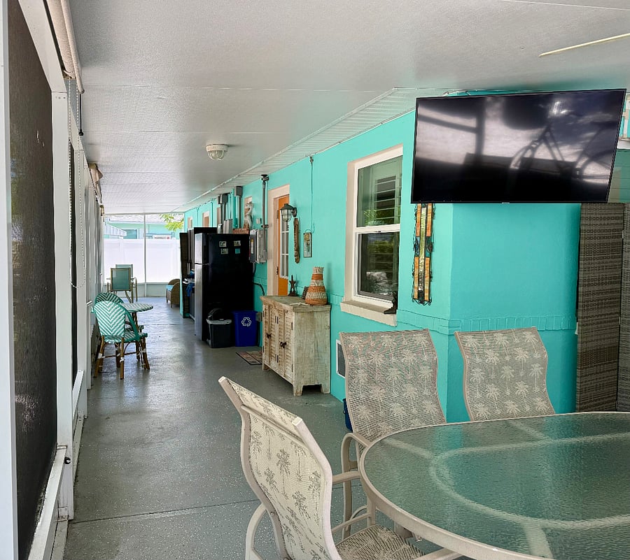 Screened lanai area with shared amenities- dining areas, extra refrigerator, TV, beach supplies, cleaning supplies, laundry