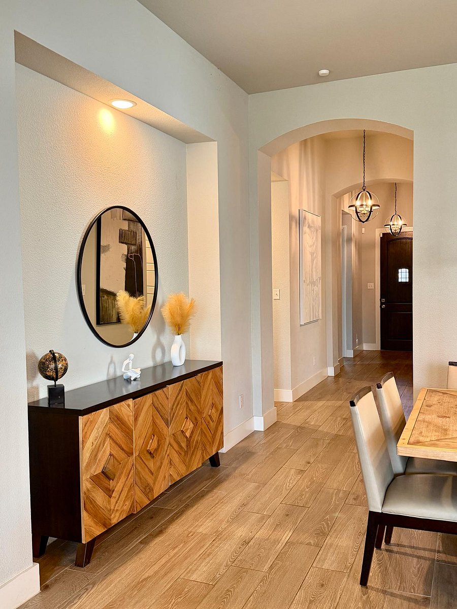 A warm welcome starts right here. Overhead light spills through the entryway, artwork lines the walls with character, and every guest steps into a home that already feels like theirs.
