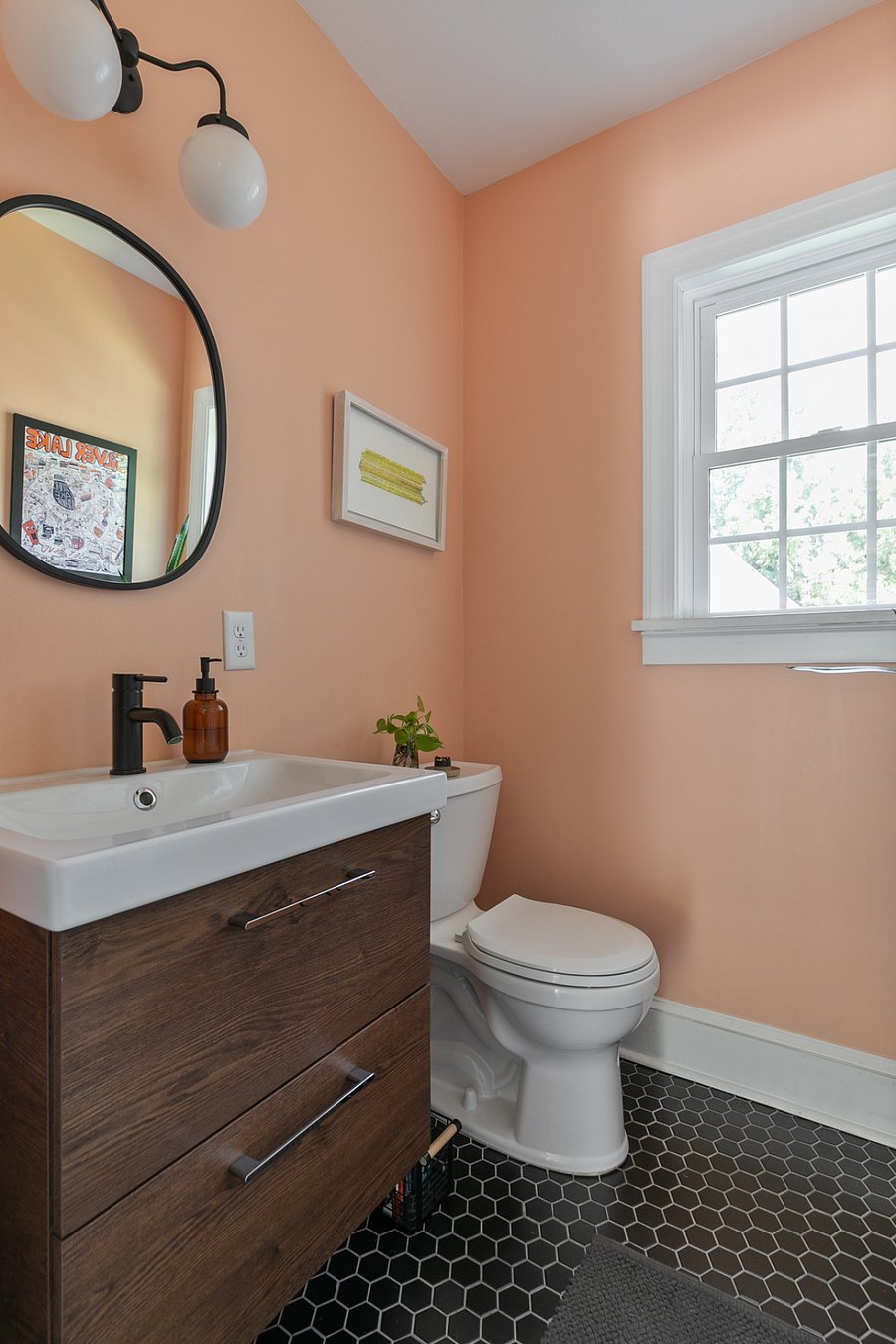 The first floor half bath features more original art complimented by a sleek black tile floor.