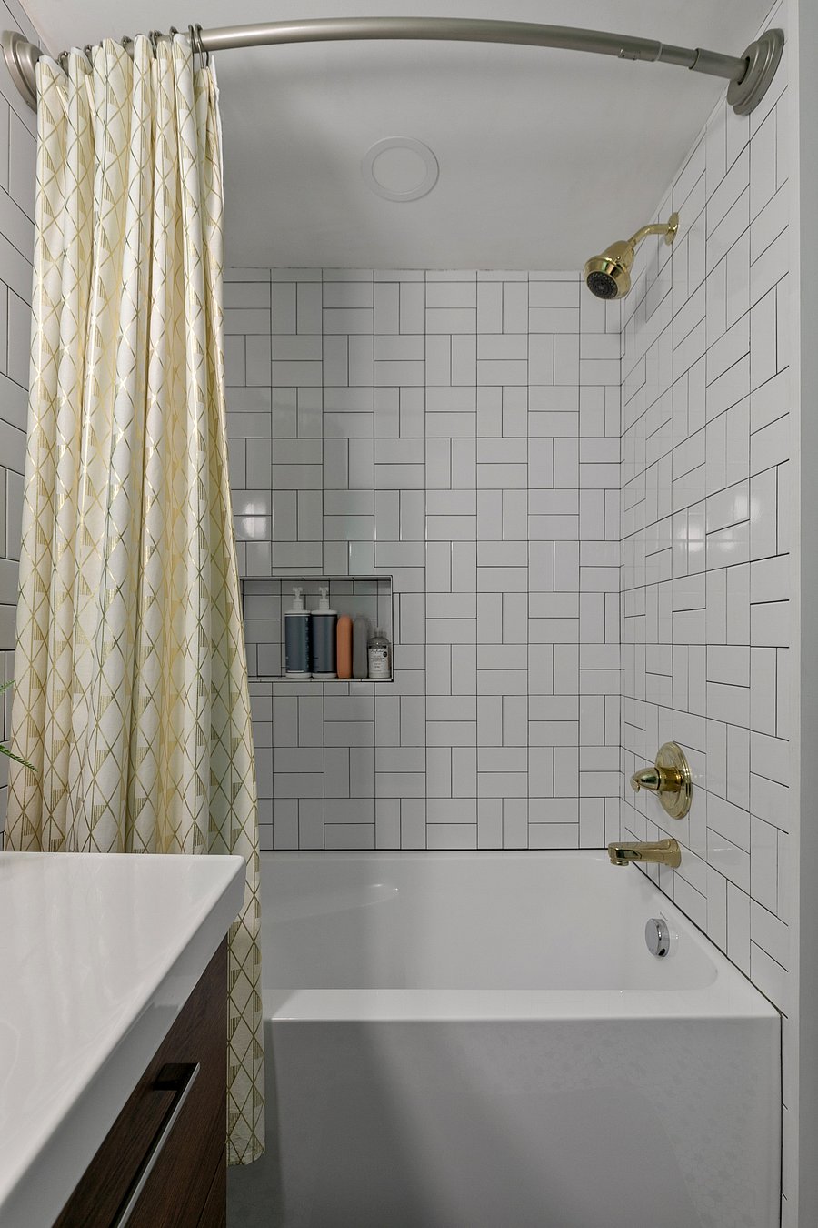 The upstairs full bath features brass fixtures and custom tile work.