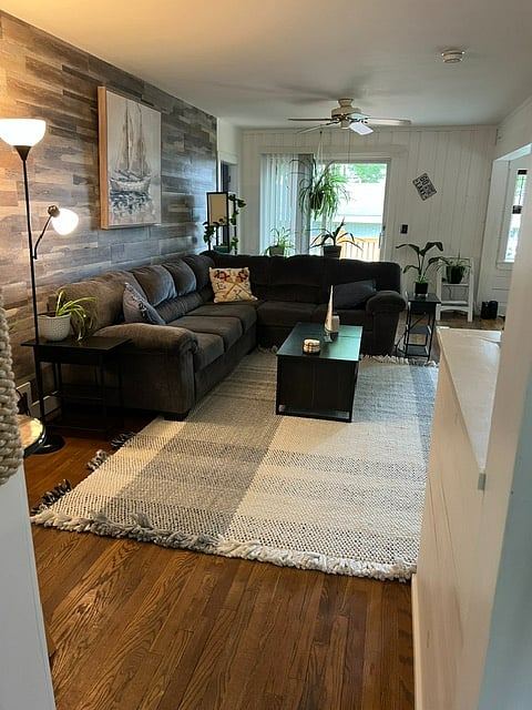 Hardwood floor with large area rug. Slider with verical blinds leading to deck and patio  in the bac yard.