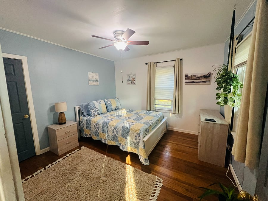 "Blue calm" Bedroom 1st floor. Queen bed, closet, dresser, nightstand, TV, AC unit, area rug on hardwood floor