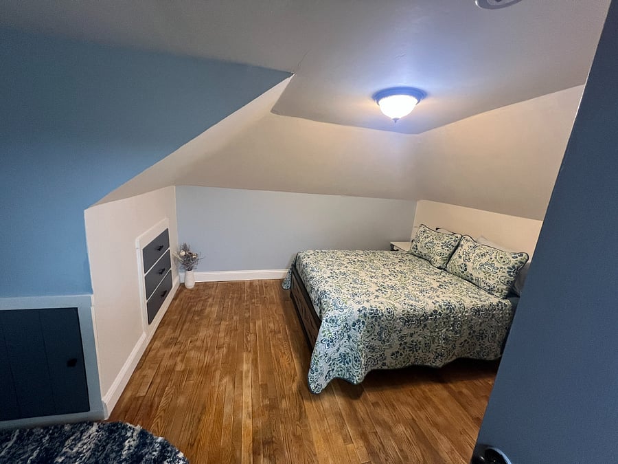 "Shoreview" Bedroom 2nd floor. Double bed, nightstand, built-in drawers and shelving, closet, desk, TV, AC unit, area rug on hardwood floor